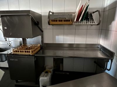 plan de travail en acier inoxydable dans une cuisine professionnelle, avec de la vaisselle et des ustensiles