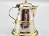 a silver coffee pot with a handle on a white surface