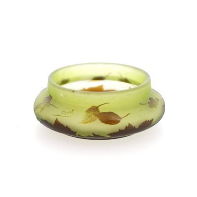 un bol en verre vert orné d'un motif de feuilles jaunes