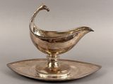un plat ancien en argent surmonté d'une soucoupe en forme d'oiseau