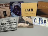 Plusieurs livres sont posés sur une table devant un mur blanc.