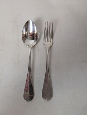 two spoons and a fork on a white table