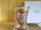 a glass vase with a heart on it sitting on a table