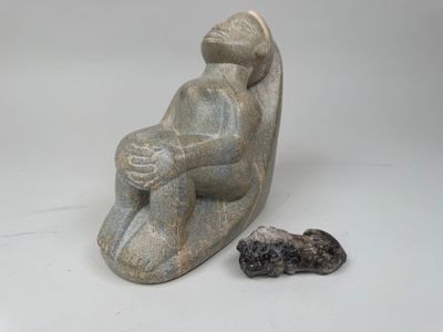 une image représentant une sculpture d'une personne assise sur un rocher