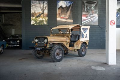 une vieille jeep garée dans un garage à côté d'autres voitures
