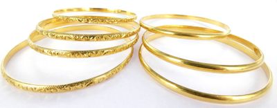 a close up of a stack of gold rings on a white surface