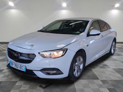 une voiture blanche est garée dans une pièce au sol à carreaux