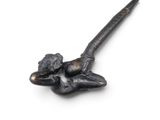 a small metal object with a long handle on a white surface