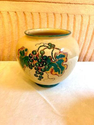 un vase blanc orné d'un motif vert et jaune