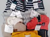 a pile of sweaters and a purse on a table