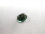a close up of a green tourmaline stone on a white surface