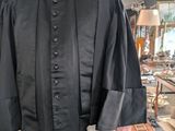 a man in a black robe standing in a room