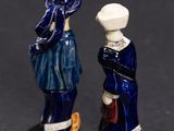 two figurines of a man and a woman standing next to each other