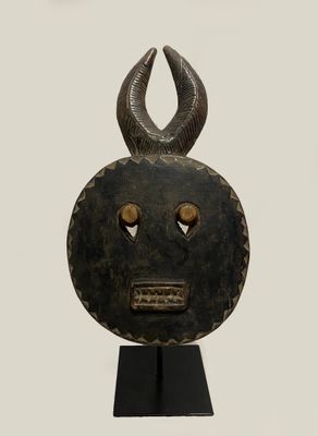 an image of a wooden mask with horns on a black stand