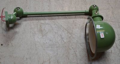 une lampe verte accrochée au mur à côté d'une lampe