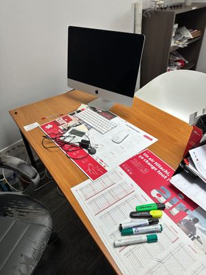 un bureau sur lequel se trouvent un écran d'ordinateur, un clavier et des papiers