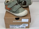 des chaussures de petit garçon dans une boîte posée sur une surface blanche