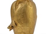 a gold vase with a bird on it on a white surface