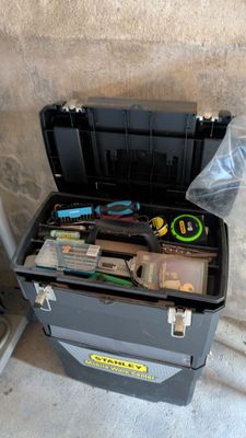 une boîte à outils contenant des outils, posée sur le sol