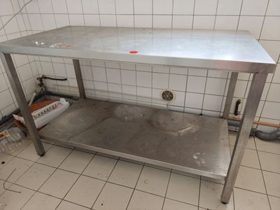 une table de travail en acier inoxydable au milieu d'une pièce carrelée