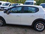 a small white car parked in a lot with other cars in the background