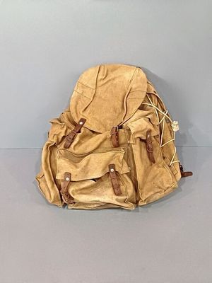 un sac à dos beige posé par terre