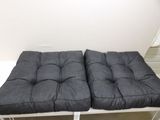 pair of grey cushions on a white bench in a white room