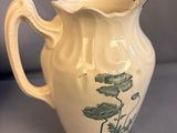 an image of a white pitcher with a green design on it