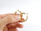a person holding a pair of gold hoop earrings in their hand