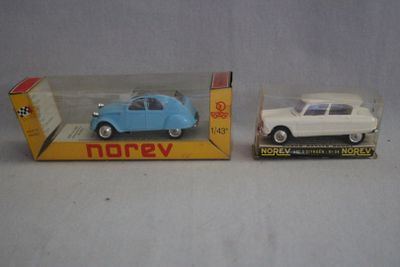 Deux petites voitures sont posées dans une boîte sur une table.