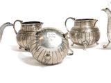 three silver teapots and a coffee pot sitting next to each other