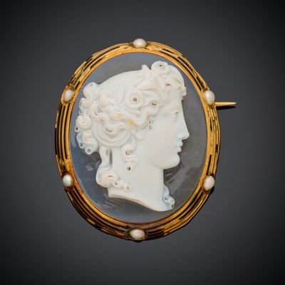 Une broche en or représente le profil d'une femme.