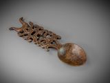 an old wooden spoon with a carved handle on a gray surface