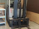 a forklift in a warehouse with a shelf on the other side