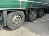 un semi-remorque vert avec un pneu crevé, garé sur un parking
