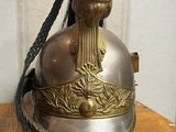 a silver helmet with a gold decoration on top of a wooden table