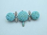 a close up of a pair of blue beads on a white surface