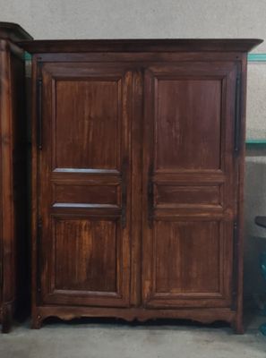 une armoire en bois à côté d'une table et d'une chaise dans une pièce