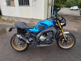 une moto bleue et noire garée devant un immeuble