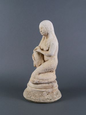 une statue de femme assise au sommet d'un rocher