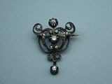 an antique silver broochle with black stones on a blue surface