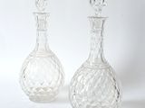 two clear glass vases sitting next to each other on a white surface