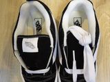 black and white vans slip on sneakers on a wooden floor