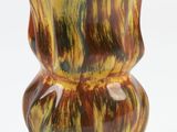 a yellow and brown vase sitting on a white surface