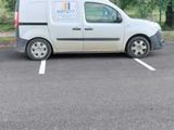 une camionnette blanche garée sur un parking avec des arbres en arrière-plan