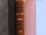 un livre marron posé sur une table, à côté d'une feuille de papier