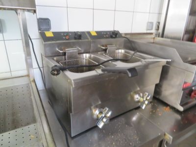 une cuisine avec de nombreux appareils électroménagers en inox posés sur le plan de travail