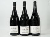 trois bouteilles de vin rouge sont alignées sur une surface blanche