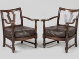 pair of leather armchairs with carved arms and wooden legs