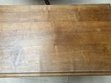 a wooden table with a glass top on a tile floor